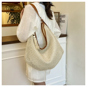 Detail of woven straw tote bag with brown leather straps and beige fringe tassel