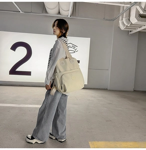 Detail eines cremefarbenen Nylon-Rucksacks mit mehreren Taschen und gepolsterten Trägern