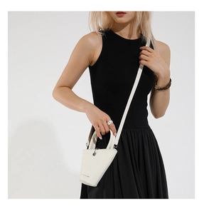 Vue détaillée d'un sac seau irrégulier blanc avec fines bandoulières et poignées