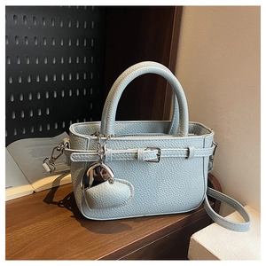 Close-up of pebble grain leather texture with heart charm on light blue handbag