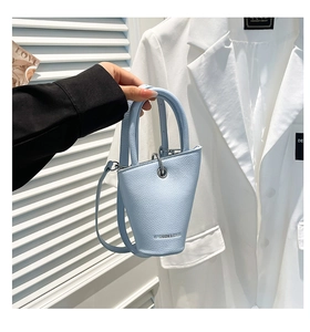Détail du sac seau en cuir bleu clair à motif litchi avec finitions argentées et poignée