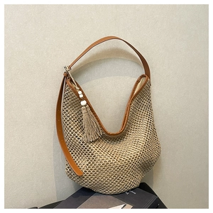 Detail of woven straw hobo bag with brown leather strap and beaded tassel charm