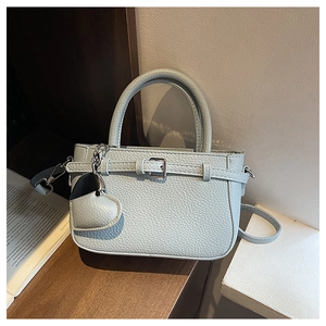 Detail of light blue lychee pattern handbag with heart pendant and silver chain accent