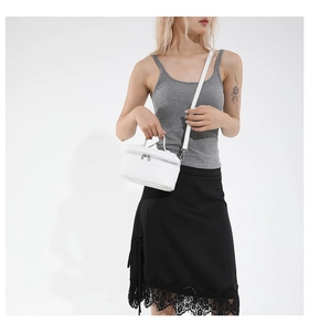 White leather handbag with silver zipper and shoulder strap shown in a lifestyle pose
