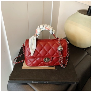 Detail of red quilted leather bag with silver turn-lock and silk scarf handle