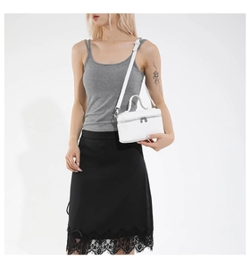 Detailed view of white leather crossbody bag with silver zipper and slim strap