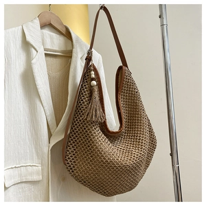 Detail of woven straw hobo bag showing intricate openwork patterns and fringe tassel