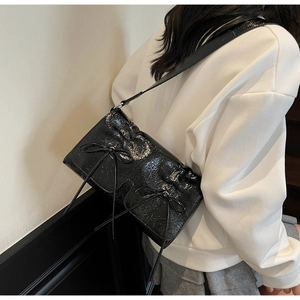Détail du sac à bandoulière en cuir verni noir froissé avec nœuds doux et plis chic