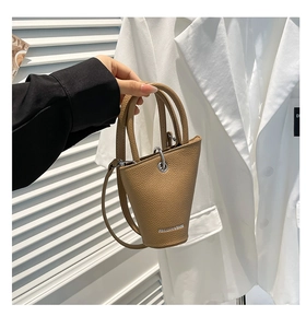 Détail du sac seau camel à texture litchi avec poignée métallique et bandoulière
