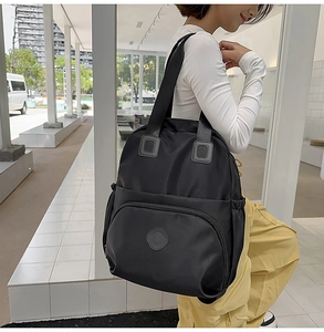 Detail eines schwarzen Nylon-Rucksacks mit kreisförmigem Logo und großer Reißverschlusstasche