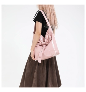 Detail der rosa Lackleder-Einkaufstasche mit Schleife und silbernen Nieten am Modell