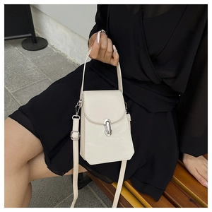 Détail d'un sac bandoulière blanc crème avec fermoir en métal ovale et bandoulière amovible
