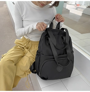 Detail eines schwarzen Nylon-Rucksacks mit Mehrfachtaschen und verstellbaren Trägern