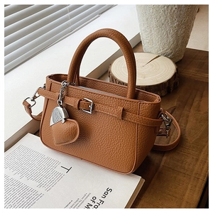 Detail of lychee pattern brown crossbody bag with heart pendant and metal buckle