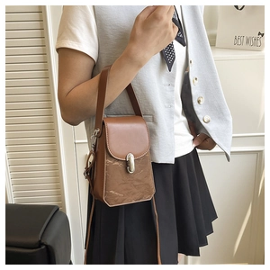Mini sac bandoulière marron avec boucle en métal porté avec chemise blanche et jupe