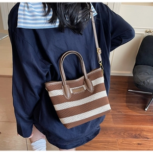 Detail der gestreiften Strick-Beuteltasche mit Ledergriffen und Markenlogo am Modell