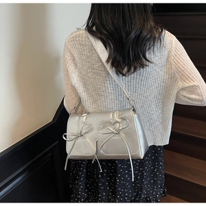 Sac bandoulière argenté avec détails nœuds et texture froissée porté par un mannequin