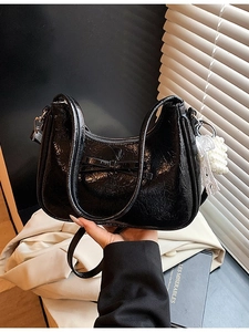 Glänzende schwarze Schultertasche mit Schleife und Perlenanhänger im eleganten Stil
