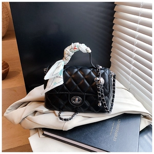 Close-up of black quilted shoulder bag with silver turn-lock and silk scarf detail