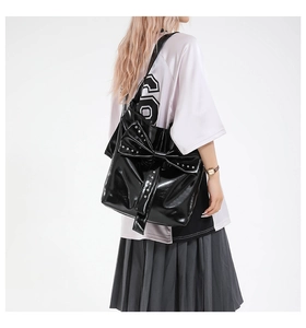 Detail der schwarzen Lackleder-Schultertasche mit XL-Schleife und silbernen Nieten