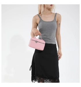 Detail of light pink pebble leather vanity bag with metal ring zipper and top handle