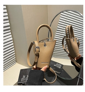 Gros plan sur le cuir grainé abricot et la boucle métallique du sac seau de créateur