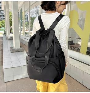 Detailansicht des schwarzen Nylon-Rucksacks mit Seitentaschen und Textur im Freien