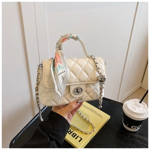 Close-up of white quilted crossbody bag with silk scarf handle and golden chain strap