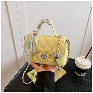Close-up of yellow quilted bag featuring a silver twist-lock and silk scarf handle detail