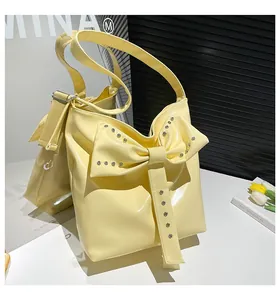 Detail der gelben Lackleder-Tasche mit großer Schleifendekoration und silbernen Nieten
