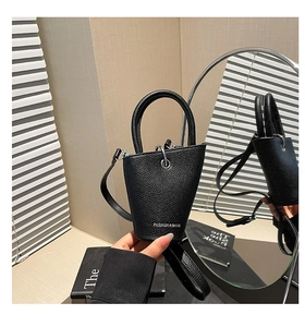 Détail du sac seau en cuir grainé noir avec logo argenté et poignée supérieure