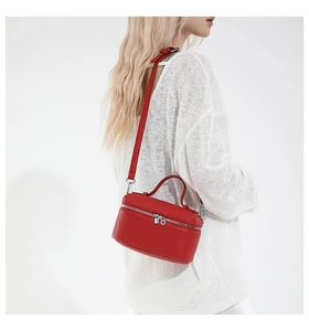 Detail of red lychee grain leather box bag with silver zippers and adjustable strap