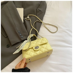 Detail of quilted yellow handbag featuring floral scarf handle and silver bottom studs
