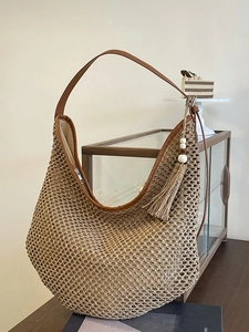Large khaki straw tote bag with brown leather straps and tassel charm for summer