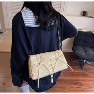 Détail du sac bandoulière crème avec nœuds décoratifs et texture plissée élégante