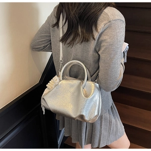 Close-up of silver pleated bucket bag with pearl pendant and rigid circular handle
