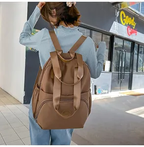 Detail eines großen braunen Nylon-Rucksacks mit Tragegriffen und Reißverschlusstasche