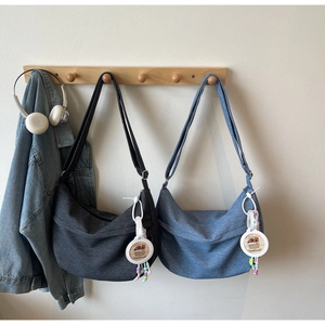 Detail of blue and grey denim dumpling bags with Capybara charms hanging on hooks