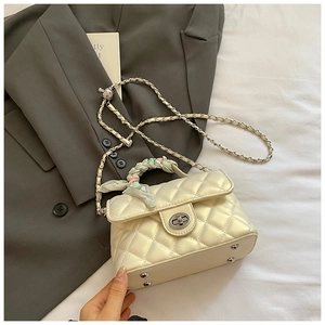 Close-up of quilted cream handbag with silk scarf handle and metal turn-lock closure