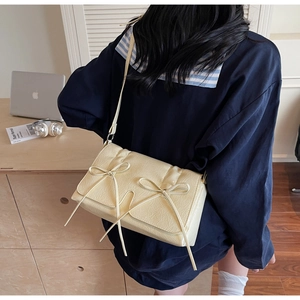 Détail du sac bandoulière jaune crème avec texture plissée douce et nœuds élégants