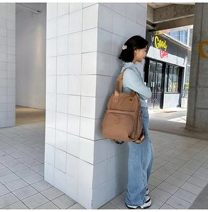Detailansicht des khakifarbenen Nylon-Rucksacks mit Fronttasche und Seitenfächern
