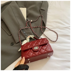 Detail of burgundy quilted handbag with silver twist lock and scarf-wrapped handle