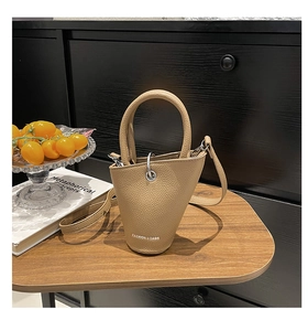 Détail du sac seau kaki avec anneau argenté posé sur une table en bois texturé
