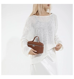 Close-up of brown litchi pattern leather handbag with silver zipper and curved handle