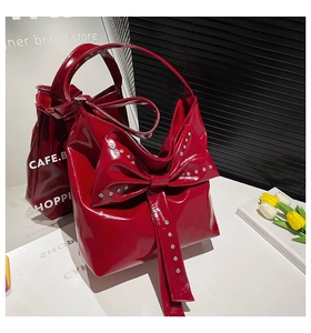 Detailaufnahme der roten Lackledertasche mit großer Schleife und silbernen Metallnieten