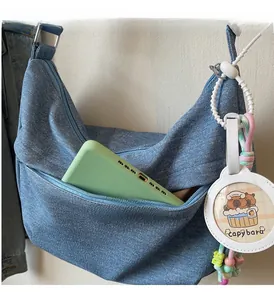 Detail of blue denim hobo bag featuring a zipper pocket and cute capybara charm