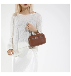 Détail d'un sac à main en cuir marron avec double fermeture éclair argentée et grain de cuir