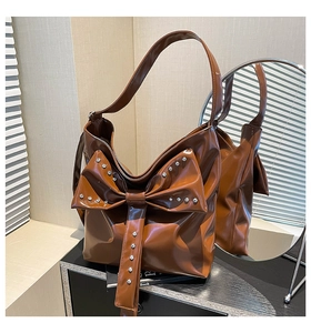 Detail der karamellbraunen Schleifen-Shopper-Tasche mit silbernen Nieten auf Hochglanz