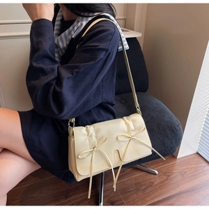 Détail d'un sac à bandoulière beige crème avec nœud élégant et texture plissée en similicuir