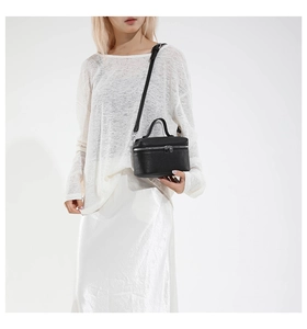 Detail of a black pebbled leather crossbody mini bag with silver zipper and slim strap